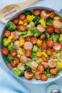 a skillet filled with broccoli, corn and sausage on top of rice