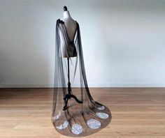 a mannequin wearing a sheer veil on top of a hard wood floor in front of a white wall