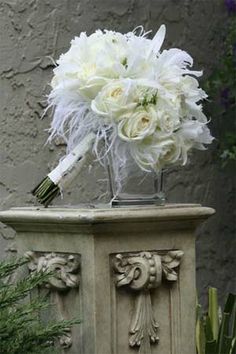 a bouquet of white flowers sitting on top of a stone planter in front of a building