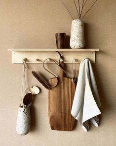 a wooden cutting board sitting on top of a wall next to utensils and a vase