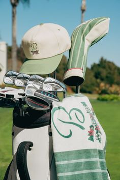 a golf bag and hat sitting on top of a green grass covered field next to a golf club