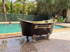 an old fashioned bathtub sitting next to a swimming pool