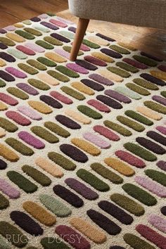 an area rug with multicolored circles on it in front of a couch and chair