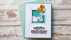 a happy birthday card with balloons and a dog on the front is displayed against a wooden background