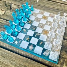 a glass chess board with shells and starfishs on the board, sitting on a wooden table