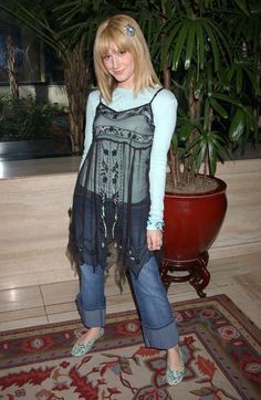 a woman standing in front of a potted plant