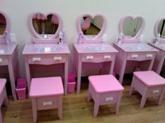 there are many pink vanitys and stools with mirrors on the wall behind them