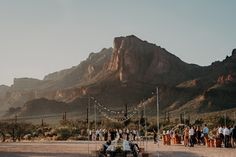 a car is parked in the middle of a desert with people standing around and looking at it