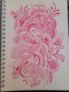 a spiral notebook with an intricate design on the front and back cover in red ink