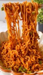 noodles are being lifted from a bowl with chopsticks in the shape of letters