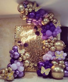 purple and gold balloons are arranged in the shape of an arch with butterflies on it