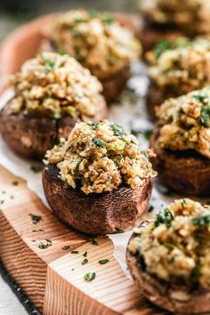 baked stuffed mushrooms on a wooden board with herbs sprinkled all over the top