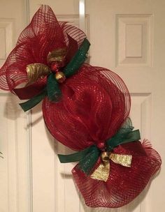 two red mesh wreaths with gold and green bows hanging on the front door for christmas