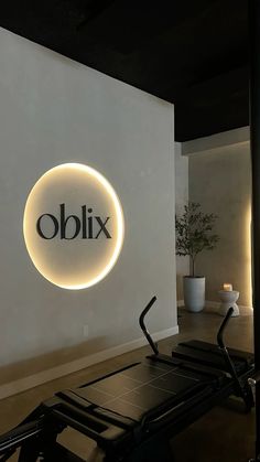 a gym with an illuminated sign and exercise equipment in front of the wall that reads oblix