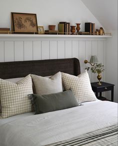 a bed with many pillows on top of it and some shelves above the headboard