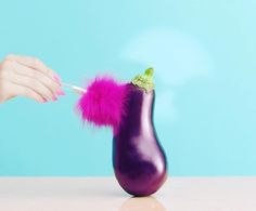 a purple eggplant with a pink pom - pom sticking out of it