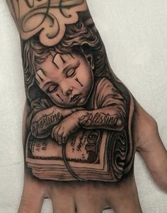 a person's hand with a tattoo on it that has an image of a boy reading a book