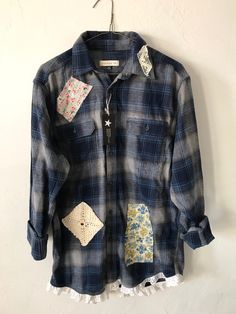 a blue and white shirt with patchwork on the front hanging from a hanger