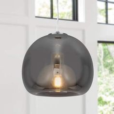 a light fixture hanging from a ceiling in a room with white walls and large windows