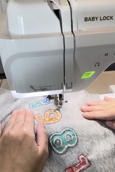 someone is using a sewing machine to sew on some appliqued items