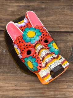 a brightly colored hand painted ceramic object sitting on top of a wooden table