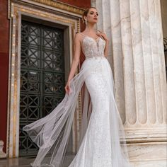 a woman in a white wedding dress standing next to columns with her long veil draped over her head