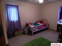 a bedroom with a bed, desk and green carpeted area in front of the window