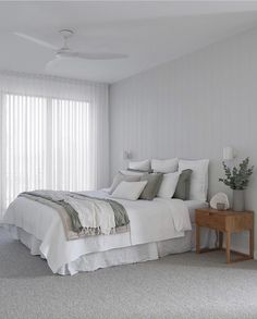 a bed with white sheets and pillows in a room