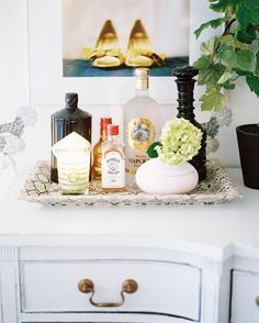 a white dresser topped with bottles and vases