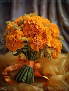 a bouquet of orange flowers sitting on top of a yellow cloth covered tablecloth next to a curtain