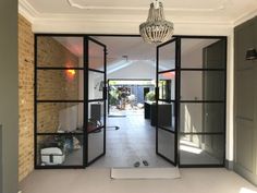 an open door leading to a living room with a chandelier hanging from the ceiling