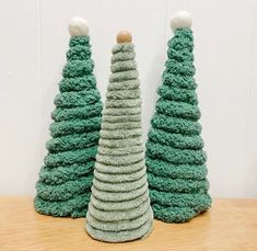 three green trees sitting on top of a wooden table