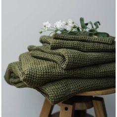 a pile of green towels sitting on top of a wooden stool next to a white flower