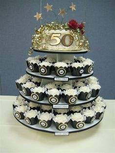 a tiered cake with cupcakes on it and a sign that says 50