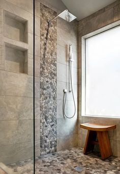 a walk in shower sitting next to a window with rocks on the wall and floor