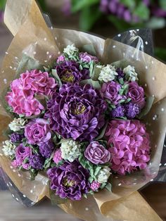 a bouquet of purple and white flowers sitting on top of a brown paper wrapper