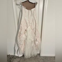 a white dress hanging on a door with a hanger in front of it that is attached to the wall