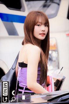 a woman with long brown hair standing next to a car