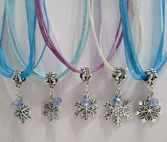 three necklaces with snowflake charms hanging from them