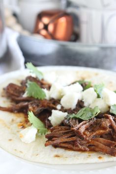 shredded beef and feta cheese are on a tortilla with cilantro