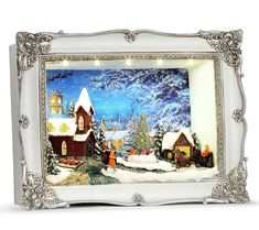 a christmas scene is shown in an ornate frame with lights on it and snow covered trees