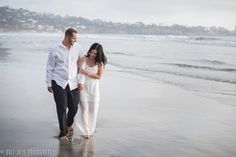 a man and woman are walking on the beach