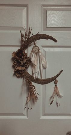 the door is decorated with feathers and pine cones