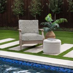 a chair sitting next to a pool with grass on the ground and a potted plant