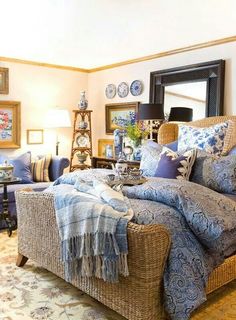 a living room with wicker furniture and blue pillows on the couches in front of a mirror