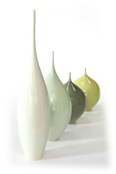 three different colored vases sitting side by side on a white surface, one is green and the other is yellow