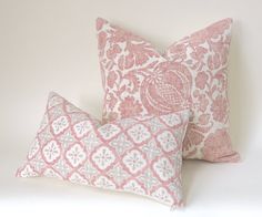 two pink and white pillows sitting next to each other