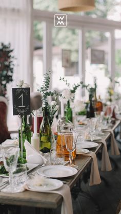 the table is set with wine bottles, plates and silverware for an elegant dinner