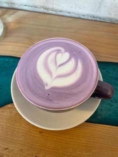 a cappuccino on a saucer sitting on top of a wooden table