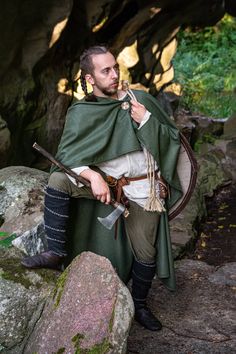 "Embrace the medieval and Viking eras with our half-circle woolen cloak, designed to fall around ankle to mid-calf level. This practical and versatile hoodless cape is perfect for traveling, LARP, reenactment, cosplay, weddings, and more. It adds a striking finishing touch to a variety of costumes, including ranger, bandit, Viking axeman, and adventurer. Offering protection from wind, rain, and cold, the cloak fastens at the collar with a button and can be styled in multiple ways, as demonstrated in the photos. Please specify your height in \"note to seller\". This is a half-circle cloak and frontal gap may look differently depending on your body constitution. Button is customizable, please write me if you want a different one. Feel free to CONTACT ME if you have any questions or wish to m Medieval Cloak Men, Medieval Costumes For Larp And Cosplay Events, Warrior Costumes For Medieval Festivals, Viking Costumes For Larp And Medieval Festivals, Viking Costume For Larp And Cosplay Events, Viking Style Medieval Dress For Festivals, Viking Costume For Medieval Festivals, Elven Cape For Cosplay And Medieval Festivals, Medieval Traveler